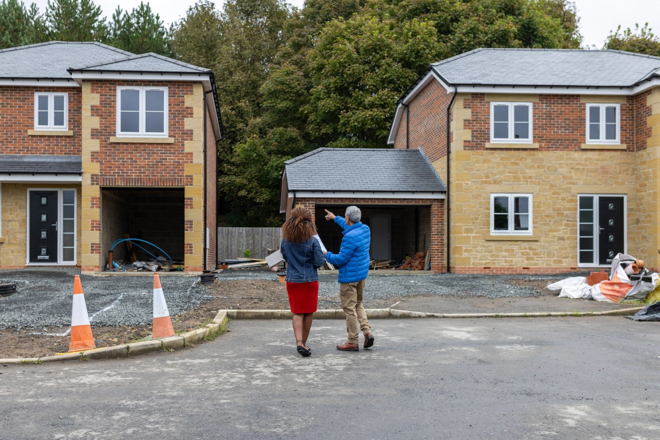 Builder reviewing plans with a client at a housing development